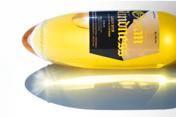 Prototype de la bouteille de bière japonaise de Kenji Abe plantée dans le sable sur une plage ensoleillée
